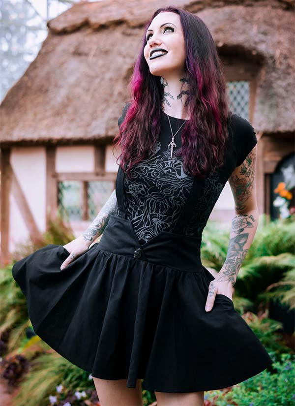 A woman wears the Dark Pixie Suspender Skirt by Dark Cottage