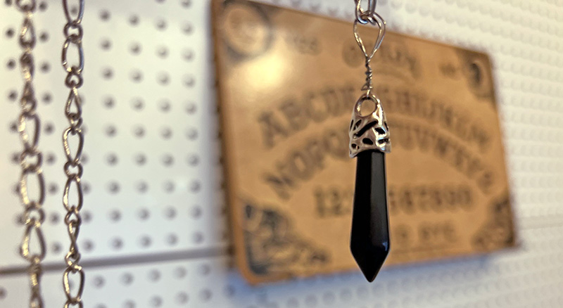 An obsidian pendulum in front of a spirit board accompanying an article about whether police work with psychics