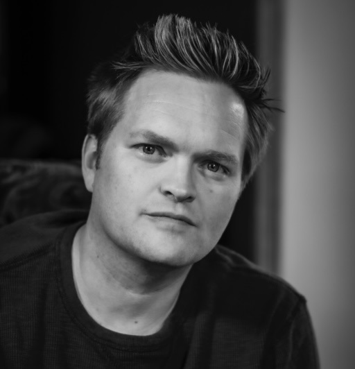 A black and white photo of Ashley Stinnett, who shares his terrifying true ghost story about how he learned that ghosts can hurt you when he was just a child.