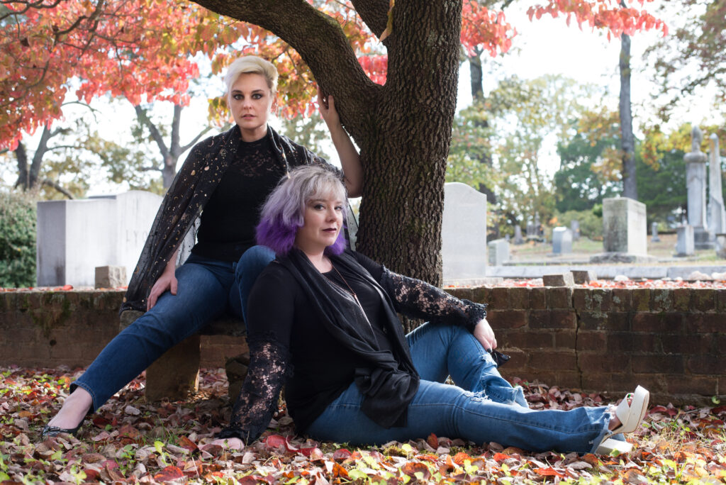 Becky and Diana lounging under a tree tinted fiery with autumn, in a cemetery in GA.