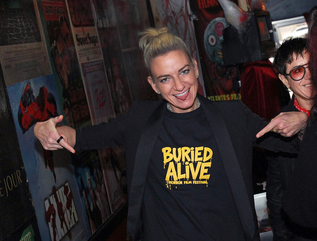An action shot of Tina Romero, director of Queens of the Dead, repping the Buried Alive horror film festival logo on her t-shirt